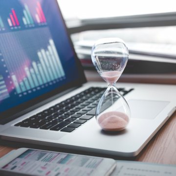 Computer with a hour glass resting on it.